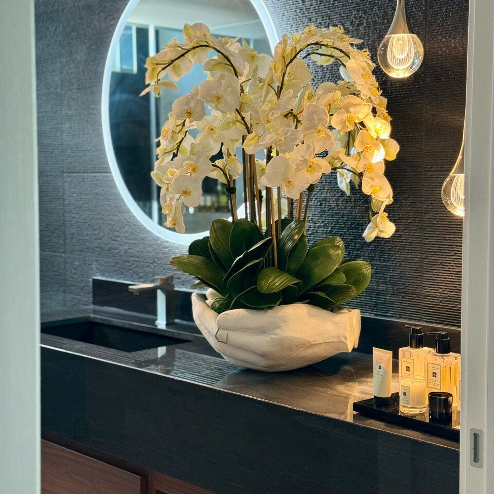 Orchidées Phalaenopsis blanches dans un vase sculpture de mains ouvertes