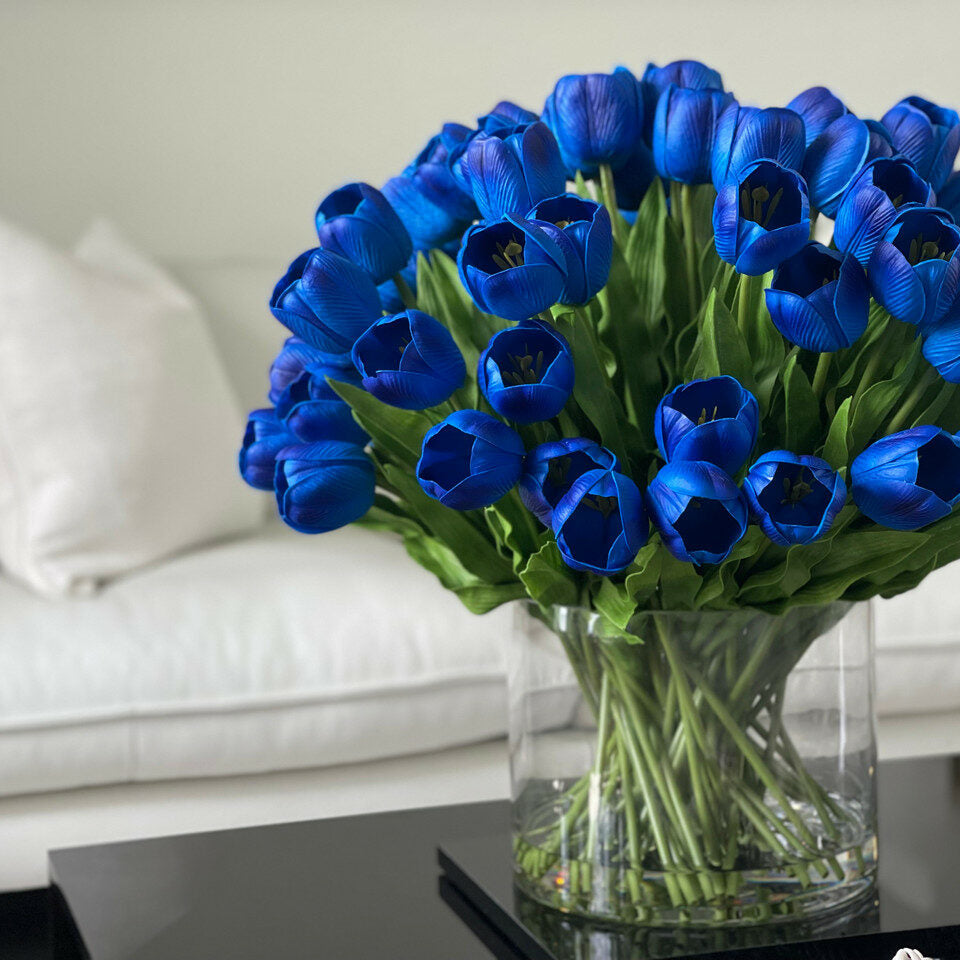Arrangement de tulipes bleues dans un grand vase cylindrique