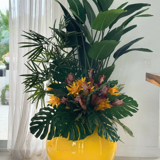 Mix de plantes tropicales dans un vase globe jaune